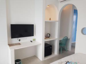 Ipoh Santorini Hideaway - Hotel Inspired في ايبوه: غرفة بها سرير وتلفزيون على الحائط