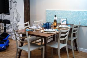 a dining room table with chairs and a bottle of wine at Apartamenty, Domki i Pokoje ze śniadaniem Kajan in Jastrzębia Góra