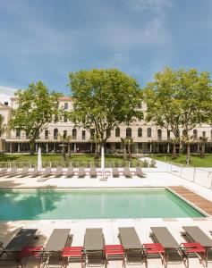 uma piscina com espreguiçadeiras e um edifício em Villages Clubs du Soleil - MARSEILLE em Marselha