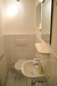 ein weißes Bad mit einem Waschbecken und einem WC in der Unterkunft Green Eilun - Hausteil 5 in Wyk auf Föhr