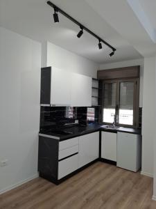 a kitchen with white cabinets and black counter tops at Erdis Home Nr 2 in Tirana