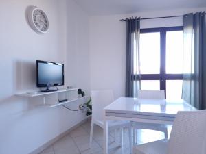 a white dining room with a table and a television at Casa Vecchio Mulino in Budoni