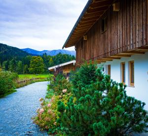 uma casa e um rio ao lado de um edifício em Amrai Appartements - Ferienwohnungen in Kreuth am Tegernsee em Kreuth