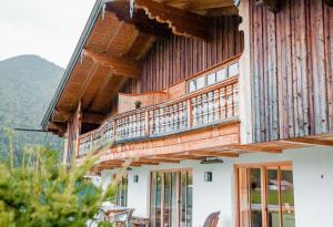 uma casa de madeira com uma varanda em cima em Amrai Appartements - Ferienwohnungen in Kreuth am Tegernsee em Kreuth