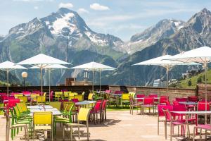 a group of tables and chairs with mountains in the background at Villages Clubs du Soleil - LES 2 ALPES in Les Deux Alpes