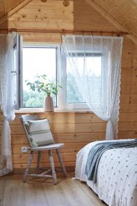 a bedroom with a bed and a window and a chair at W Brzozowym Gaju Lubiatowo in Lubiatowo