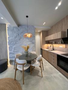 a kitchen with a table and chairs and a stone wall at Poema Antiparos in Antiparos