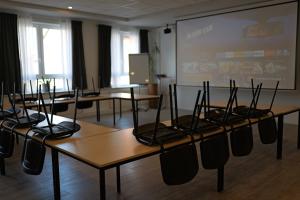 ein Klassenzimmer mit Tischen und einer Leinwand in der Unterkunft Hotel Milano in Hildesheim