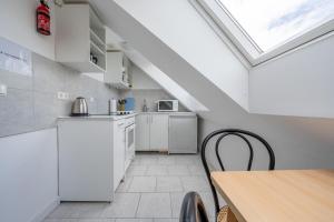 een keuken met witte apparatuur en een tafel en een dakraam bij Private Apartment in Hannover