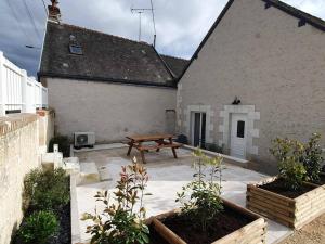 a patio with a wooden picnic table in front of a building at Un Nid en Sologne in Contres