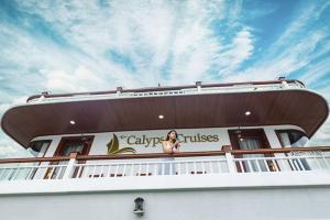 a woman sitting on the balcony of a cruise ship at Le Journey Calypso Pool Cruise Ha Long Bay in Ha Long