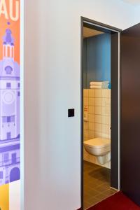 an open door to a bathroom with a toilet at McDreams Hotel Leipzig in Leipzig