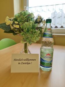 a bottle of water sitting next to a vase of flowers at Ferienwohnung im Zentrum Zwickaus in Zwickau