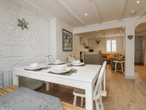 uma sala de jantar branca com uma mesa e cadeiras brancas em Riversdale Cottage em Wadebridge