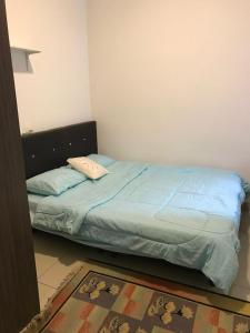 a bedroom with a bed with blue sheets and a rug at Palas Horizon in Kabus in Brinchang