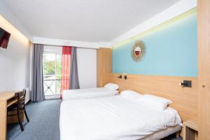 a hotel room with two beds and a desk at Villages Clubs du Soleil - MONTGENEVRE in Montgenèvre