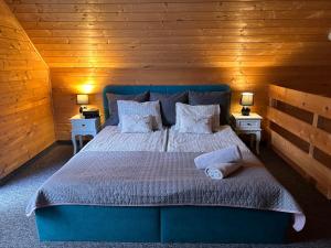 a bedroom with a blue bed with two tables and two lamps at Resort EDEN - domki, pokoje, apartamenty in Jastrzębia Góra