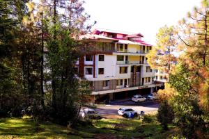 un bâtiment avec des voitures garées dans un parking dans l'établissement Hotel Blue Magnets Dalhousie, à Dalhousie