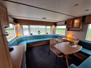 BurumStacaravan Elly, Minicamping de Grutte Earen的客厅里有一张蓝色的沙发和一张桌子