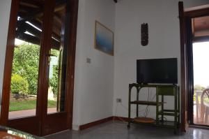 salon z telewizorem z płaskim ekranem obok drzwi w obiekcie Via dei Ciclamini - FPO-NETT01 w mieście Porto Ottiolu