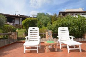 dwa białe krzesła i stół na patio w obiekcie Via dei Ciclamini - FPO-NETT01 w mieście Porto Ottiolu
