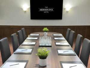 uma sala de conferências com uma mesa longa e cadeiras em The Aberdeen Dyce Hotel em Dyce