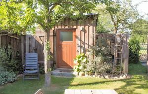 a shed with a door and a chair in a yard at 1 Bedroom Cozy stacaravan In Warthe in Warthe