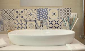 um lavatório branco numa casa de banho com azulejos azuis e brancos em B&B I 3 Mori em Barcellona-Pozzo di Gotto