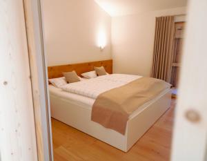 um quarto com uma cama branca num quarto em Amrai Appartements - Ferienwohnungen in Kreuth am Tegernsee em Kreuth