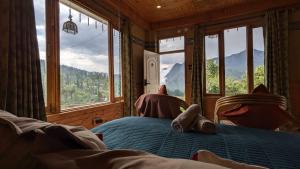 a bedroom with a bed with a view of the mountains at Hiraeth Shangarh, Sainj Valley in Shangarh