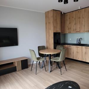 een kamer met een tafel en stoelen en een keuken bij NATURA apartament in Malbork