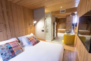 1 dormitorio con cama blanca y paredes de madera en La Maison Rouge, en Barberaz