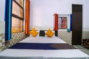 a bedroom with a bed with orange and blue pillows at SPOT ON APNA LOUDGE in Ghaziabad