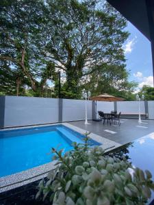 a swimming pool with a table and a umbrella at LYL Jaccuzi Private Pool House in Ipoh