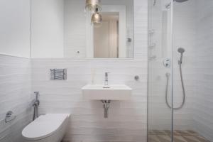 a white bathroom with a sink and a shower at Palace Dlazdena – Stylish Prague Centre Apartment in Prague