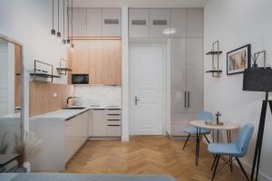 a kitchen with white cabinets and a table and chairs at Palace Dlazdena – Stylish Prague Centre Apartment in Prague