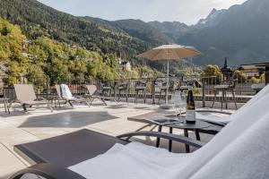 une terrasse avec des chaises, des tables et un parasol dans l'établissement MYALPS Tirol, à Oetz