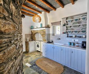 a kitchen with blue cabinets and a stone wall at Tinoshomelidays Residences in Venardatos