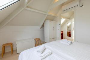 een witte slaapkamer met een bed en een raam bij Vakantiehuis - Middelburgsestraat 61a - Koudekerke 'Villa Querina' in Koudekerke
