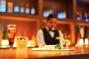 un hombre en esmoquin sentado en un bar con un plato de comida en Spa and Resort Hotel Solage Oita Hiji Beppuwan en Beppu