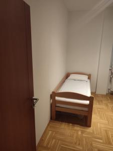 1 dormitorio pequeño con 1 cama y suelo de madera en Apartman Mia, en Požarevac
