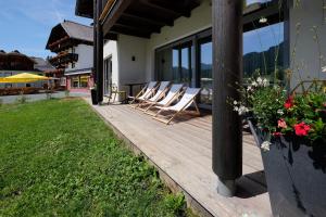 a group of chairs sitting on a wooden deck at See-Apartments Kärntnerhof in Weissensee