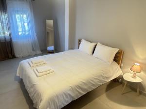 ein Schlafzimmer mit einem großen weißen Bett mit einer Lampe in der Unterkunft Seaside Luxury Apartments in Porto Rafti