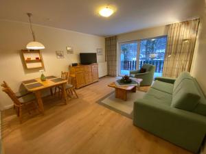 Ferienresidenz-an-der-Bode-Wohnung-2 في برونلاغ: غرفة معيشة مع أريكة خضراء وطاولة