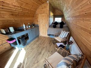 a room with a bed and a kitchen in a log cabin at The Pod Patch - Trelerney Pod in Bishops Castle