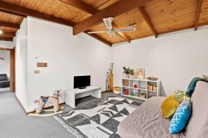 een woonkamer met een bed en een televisie bij Beachside Weekender Retreat with Spa sleeps 11-13 in Ocean Grove