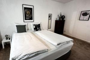 um quarto com uma cama grande com lençóis brancos e almofadas em Stadtoase nähe Uni Design Wohnung mit 2 Schlafzimmern & Sauna em Koblenz