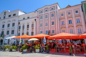 eine Gruppe von Menschen, die an Tischen unter orangefarbenen Sonnenschirmen sitzen in der Unterkunft Appartement-Hotel GH Zum Goldenen Schiff in Enns