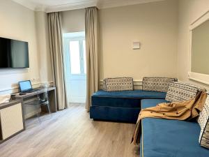 een woonkamer met een blauwe bank en een televisie bij Hotel Michelangelo in Sorrento