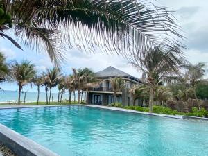una piscina davanti a una casa con palme di Starlight Villa Beach Resort a Phan Thiet